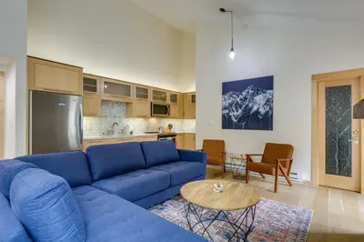 a living room with a blue couch and a kitchen at Ski Retreat Keystone Resort Condo with Heated Pool! in Keystone