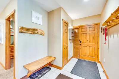 a hallway with a wooden door and a bench at Walk to Gondola Condo with Deck in Winter Park! in Winter Park