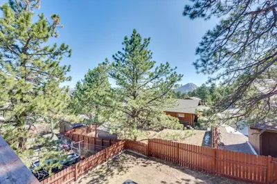 a view of the backyard of a house with a fence and trees at 2 Mi to Lake Estes Home with Deck and Grill in Estes Park