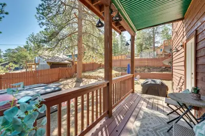 a wooden porch with a green roof and a fence at 2 Mi to Lake Estes Home with Deck and Grill in Estes Park
