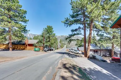 an empty road with trees and cars parked on the side at 2 Mi to Lake Estes Home with Deck and Grill in Estes Park