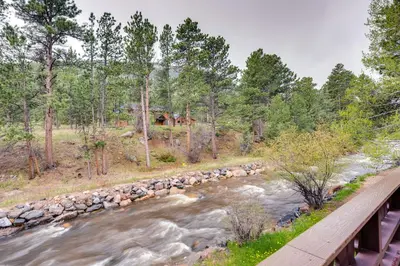 a bridge over a river next to a forest at Estes Park Condo Rental Balcony with River Views! in Estes Park