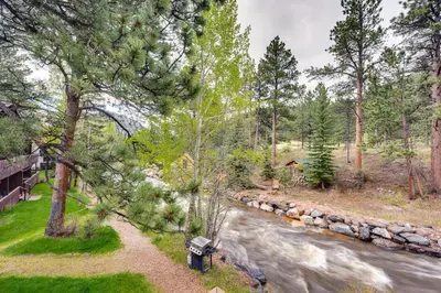 a view of a river with a bench and trees at Estes Park Condo Rental Balcony with River Views! in Estes Park