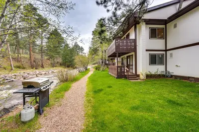 a house with a grill in front of a yard at Estes Park Condo Rental Balcony with River Views! in Estes Park