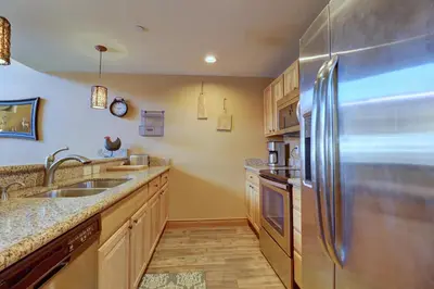 a kitchen with a stainless steel refrigerator and wooden cabinets at E8 Drake Landing 2Br Loft condo in Frisco