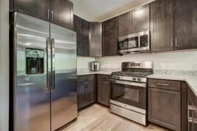 a kitchen with wooden cabinets and a stainless steel refrigerator at Clearwater Lofts - 3 Bedroom Luxury Condo Near Lakeside Village in Keystone