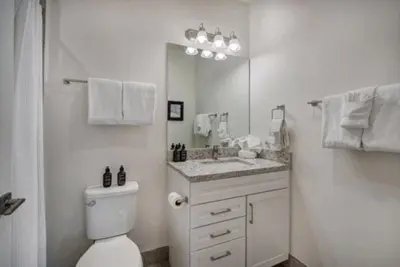 a white bathroom with a toilet and a mirror at Clearwater Lofts - New! Modern 2 Bedroom Near Keystone Lake in Keystone