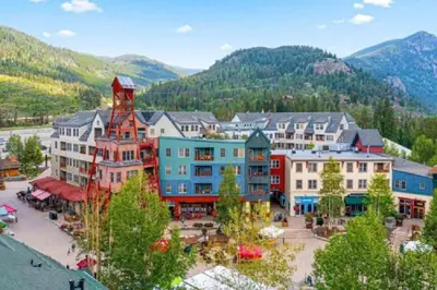 a group of buildings with mountains in the background at River Run Village Condos - 2 Bedroom - Walk To Lift! in Keystone