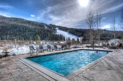 a swimming pool with chairs and a snow covered mountain at River Run Village 2 Bedroom At Red Hawk in Dillon