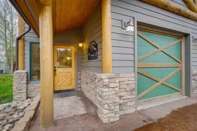 a garage with a green door and a stone wall at Fraser Vacation Rental 6 Mi to Ski Resort in Fraser