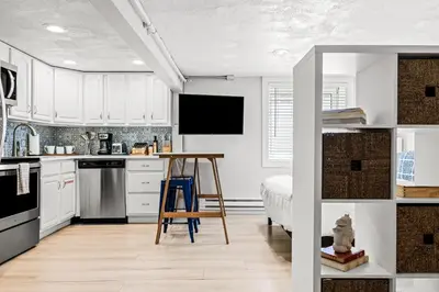a kitchen with white cabinets and a table and a bed at Contemporary Finishes - Studio Apt - Sloans Lake in Denver