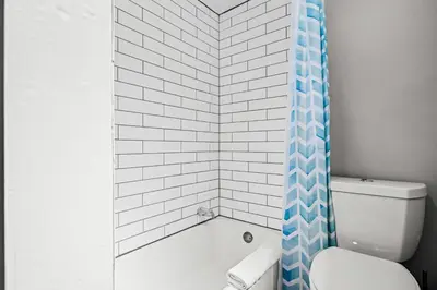 a bathroom with a blue shower curtain and a toilet at Contemporary Finishes - Studio Apt - Sloans Lake in Denver