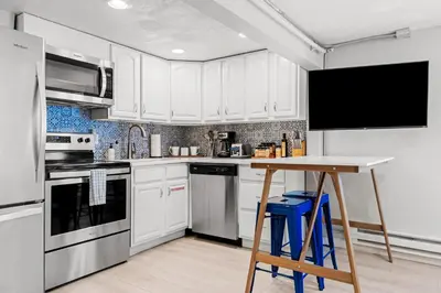 a kitchen with white cabinets and a table with stools at Contemporary Finishes - Studio Apt - Sloans Lake in Denver