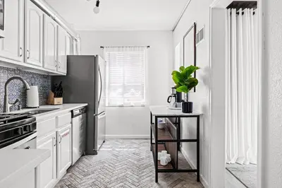 a kitchen with white cabinets and a stainless steel refrigerator at New Stylish Sanctuary - King Beds - Sloans Lake in Denver