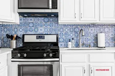 a kitchen with white cabinets and a stove and a sink at New Stylish Sanctuary - King Beds - Sloans Lake in Denver