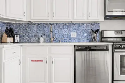 a kitchen with white cabinets and a dishwasher at Modern Comfort - King Beds - Walk to Sloans Lake in Denver