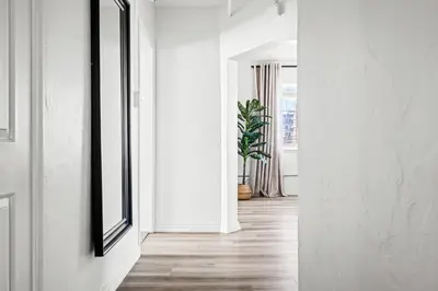 a hallway with white walls and a mirror and a plant at Modern Comfort - King Beds - Walk to Sloans Lake in Denver