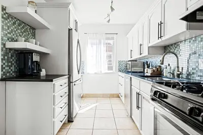a kitchen with white cabinets and black counter tops at Bright & Modern Retreat - King Beds - Sloans Lake in Denver