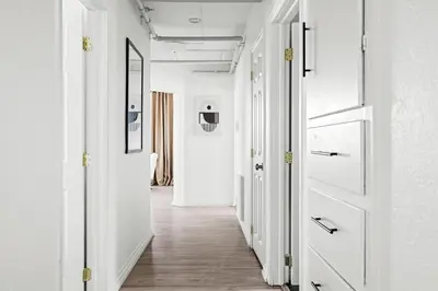 a hallway with white walls and white doors and wood floors at Bright & Modern Retreat - King Beds - Sloans Lake in Denver