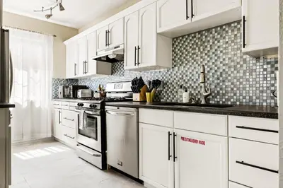 a white kitchen with white cabinets and appliances at Stylish City Retreat - King Beds - Walk to Sloans Lake in Denver