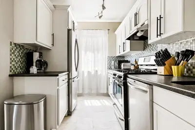 a kitchen with white cabinets and stainless steel appliances at Stylish City Retreat - King Beds - Walk to Sloans Lake in Denver