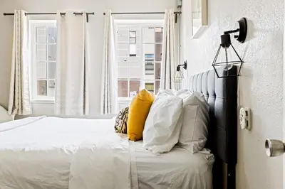 a bedroom with a bed with white sheets and yellow pillows at Stylish City Retreat - King Beds - Walk to Sloans Lake in Denver