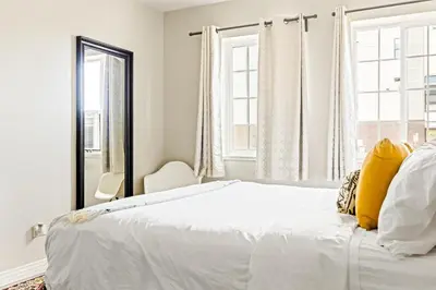 a white bedroom with a large bed with yellow pillows at Stylish City Retreat - King Beds - Walk to Sloans Lake in Denver