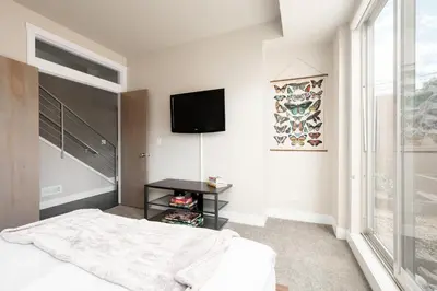 a bedroom with a bed and a tv on the wall at Center of LoHi - Roof Deck - Walk Everywhere in Denver