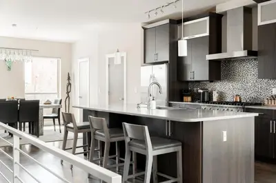 a kitchen with black cabinets and a bar with chairs at Center of LoHi - Roof Deck - Walk Everywhere in Denver