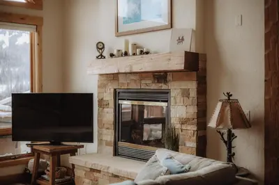 a living room with a fireplace with a flat screen tv at Hot Tub MTN Views - Free Shuttle - Central WP in Winter Park