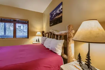 a bedroom with a wooden bed with a red bedspread at 42 Burgundy 4Br 3,5Ba townhouse in Silverthorne