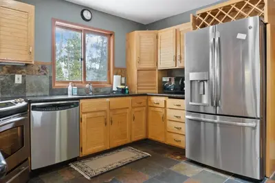 a kitchen with wooden cabinets and a stainless steel refrigerator at 5BR Mountain Retreat with Hot Tub and Sauna in Silverthorne