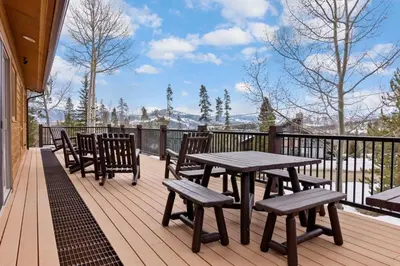 a wooden deck with a picnic table and chairs at 5BR Mountain Retreat with Hot Tub and Sauna in Silverthorne