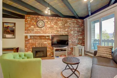 a living room with a brick fireplace and a tv at A203 Treehouse in Silverthorne