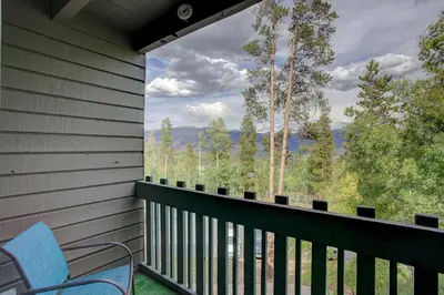 a balcony with a blue chair and a view of the mountains at A203 Treehouse in Silverthorne