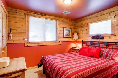 a bedroom with a bed with wooden walls and windows at 597 Deerpath in Dillon