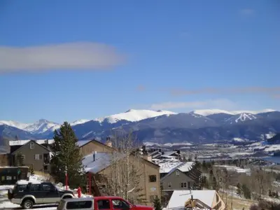 a snow covered city with cars parked in front of mountains at B-101 Buffalo Ridge in Silverthorne