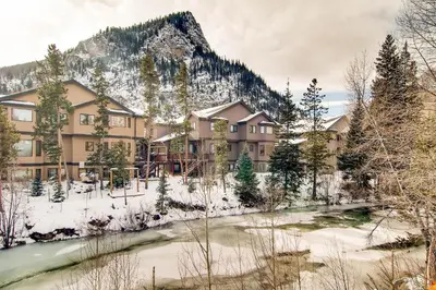 a lodge in the snow next to a river at Ten Mile Island C220 in Frisco