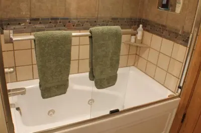 a bathroom with a bath tub with two green towels at Three Peaks Mountain Lodge in Silverthorne