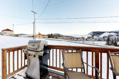 a grill on a deck with two chairs and snow at Hummingbird House in Silverthorne