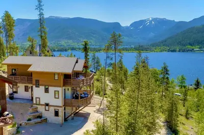 an aerial view of a house with a lake and mountains at Ski Shores- The Chalet cabin in Grand Lake