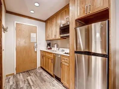 a kitchen with wooden cabinets and a stainless steel refrigerator at Keystone Slopeside Studio Condo in Keystone