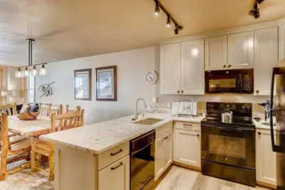 a kitchen with white cabinets and a dining room at River Run Village 3 Bedroom Condo in Keystone