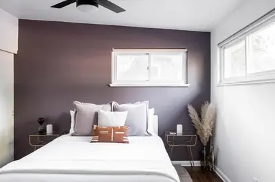 a bedroom with a large white bed and two windows at Chic Mid-Century Home Near Olde Town Arvada in Arvada
