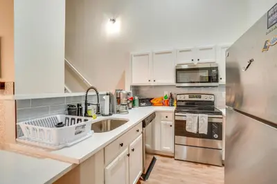 a kitchen with white cabinets and a stainless steel refrigerator at 16 Mi to DIA Townhome with Fireplace in Aurora in Aurora