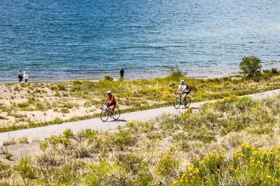 two people riding bikes on a path near the water at 8045 Black Bear condo in Keystone
