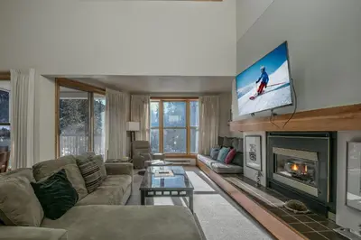 a living room with a tv above a fireplace at Quicksilver 1677 by SummitCove Lodging in Keystone