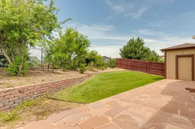 a backyard with a brick fence and a yard with a lawn at Spacious Aurora Home 20 Mi to Downtown Denver! in Aurora