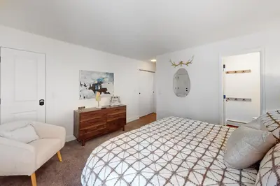 a white bedroom with a bed and a chair at Mountain Vista Retreat in Winter Park