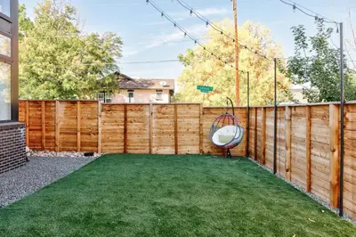 a backyard with a wooden fence and a swing at Luxe Getaway - Yard & Roof Deck - 4 Story Townhome in Denver